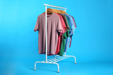 Obraz premium Colorful clothes hanging on rack against light blue background