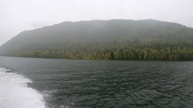 View from the boat on the shores of lake Teletskoye on a rainy autumn day