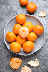 Fresh ripe tangerines and peel on grey table, flat lay