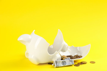 Broken piggy bank with money on yellow background