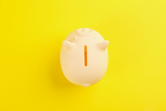 Beige piggy bank on yellow background, top view