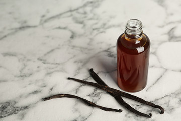 Aromatic homemade vanilla extract on marble table. Space for text