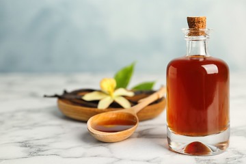 Aromatic homemade vanilla extract on marble table. Space for text