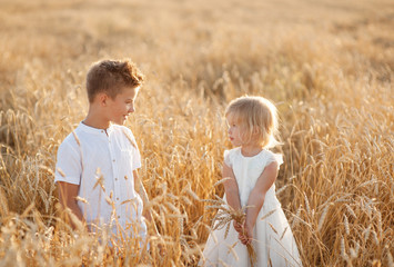 boy and girl walking in field of wheat