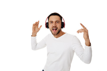 handsome young bearded man in headphones listening to music and dancing isolated on white background.