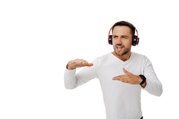 handsome young bearded man in headphones listening to music and dancing isolated on white background.