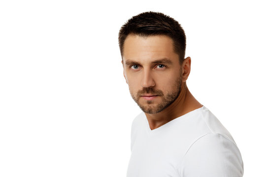 man gazes steadily. Close-up portrait of handsome bearded man in white shirt looking at camera isolated on white background