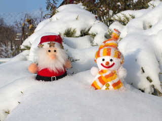Santa Claus and Snowman in the snow under a Christmas tree on a frosty winter day.