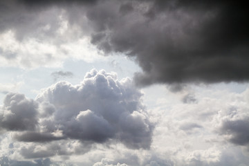 Cloudy sky with sunlit bright clouds as well as dark rain clouds