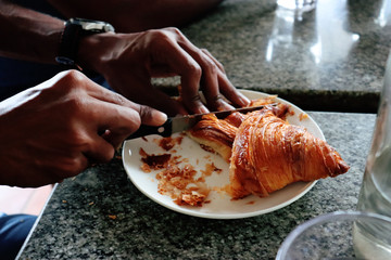 man cutting croissant for breakfast
