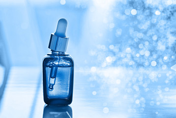 Bottle with fluid collagen of hyaluronic acid. Toned blue. Close-up.