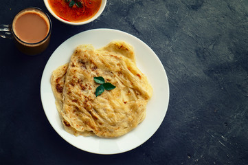 Top view of roti canai, tea and curry with space for text