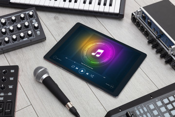 Playing song on tablet with electronic music instruments around