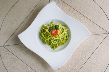 green spinach spaghetti with cheese and tomato on wooden table