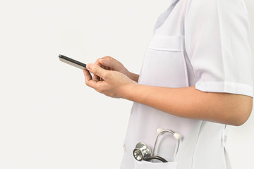 Confident young woman doctor using smartphone with stethoscope in her pocket and stand over white background.