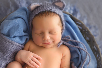 Newborn baby. Newborn boy smiles in his sleep. Newborn baby boy in a blue hat with ears.