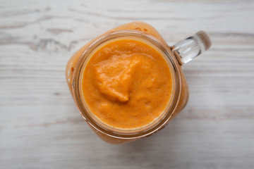Homemade pumpkin smoothie in a glass jar on a white wooden background. Flat lay, overhead, from above. Close-up.