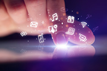 Finger touching tablet with hologram application icons and dark background