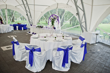 Beautiful wedding set decoration in the restaurant. Chairs with violet ribbons.
