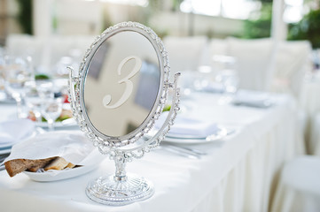 Beautiful wedding set decoration in the restaurant. Number 3 on table.