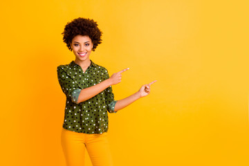 Portrait of positive cool afro american girl promoter point index finger copyspace indicate ads promo suggest select wear stylish pants isolated over bright color background