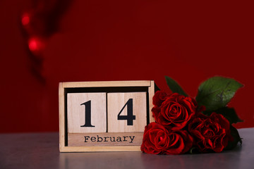 Wooden cube calendar with 14th february date, beautiful red roses bouquet. Happy st. valentine's day concept. Close up, copy space, front view