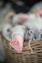 Obraz premium A beautiful soft delicate warm young baby foot photographed with a shallow depth of field. gentle calm colours and feel. baby care and well being. babies feet in a wooden basket
