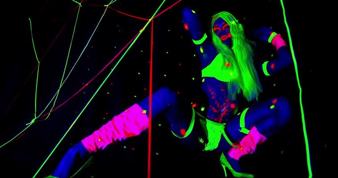 Female dancer in ultraviolet light is dancing, swinging from side to side, 4k