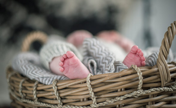 A beautiful soft delicate warm young baby foot photographed with a shallow depth of field. gentle calm colours and feel. baby care and well being. babies feet in a wooden basket