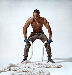 Sweaty man resting after working out with ropes. Photo of sporty man relaxing during workout on...