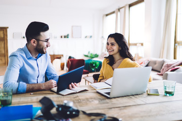 Pleased couple taking notes and browsing gadgets