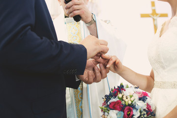 Nowożeńcy nakładają obrączki podczas wypowiadania słów przysięgi małżeńskiej.