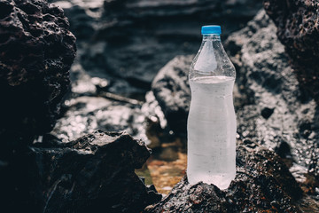 Bottle with mineral water in the nature among stones and grass
