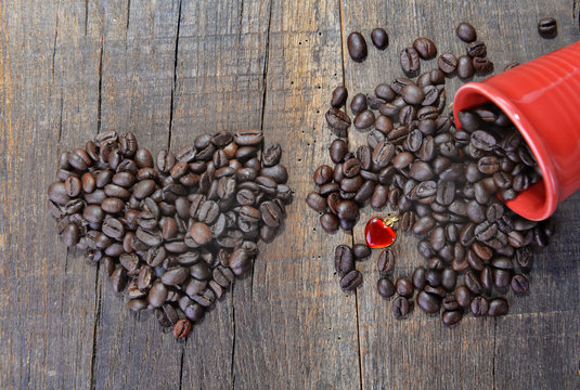 heart shaped in coffee  beans  and a spilled red cup with a heart shaped jewel-concept