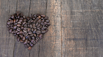 heart shaped making with beans of coffee arranged on a rustic plank with copy space on the right - Powered by Adobe
