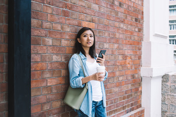 Asian woman standing front of wall with coffee