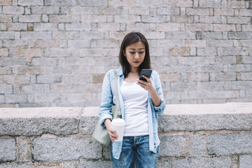 Pretty Asian woman texting and holding coffee