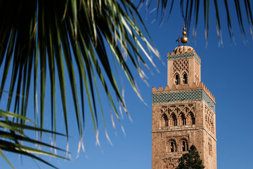 The Koutoubia Mosque or Kutubiyya Mosque with palm tree leaves in foreground, Marrakesh, Morocco