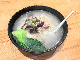 A bowl of stewed chicken noodles with mushroom is set on the table