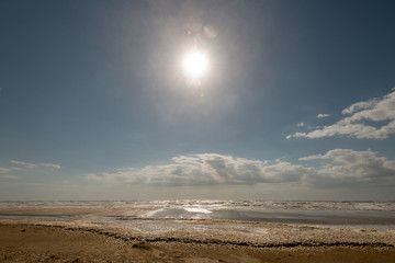 Fototapeta na wymiar Surf with sea foam with the sun on a slightly cloudy sky