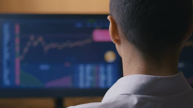 Male businessman is studying sales charts on a computer monitor. The broker is watching stock sales statistics. Investment concept