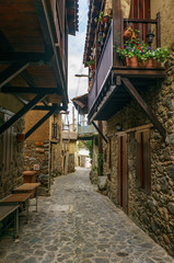Ancient village Kakopetria in Cyprus - travel architecture background. Stunning view of the street in old town. Pots with flowers standing on paved pavement along stone wall