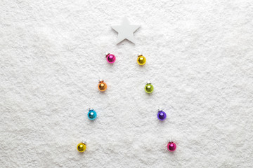 Christmas background abstract made of multicolored decoration baubles as fir tree and white star in snow.