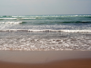 Ocean wave and wet sand on a beach, abstract nature background.