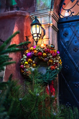 Christmas wreath on door under retro vintage lantern on Christmas eve in beautiful fairy tale lighting in european old town city. Outdoor christmas and new year decoration