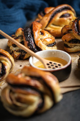 Homemade buns with dark chocolate and honey on craft paper on a dark background.