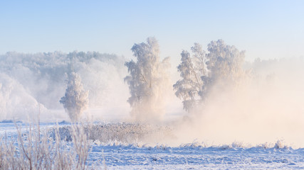 Winter nature. Snowy scene on riverside. Beautiful winter landscape. Christmas background. Misty frosty morning on river. White  nature landscape with hoarfrost