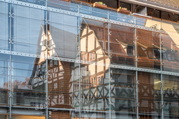 Moderne Glasfassade und sich spiegelnde Fachwerkhäuser als architektonischer Kontrast im Stadtzentrum von Erfurt