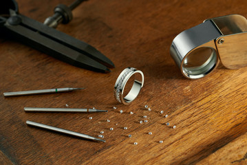 Workplace of a jeweler. Tools and equipment for jewelry work on an antique wooden desktop....