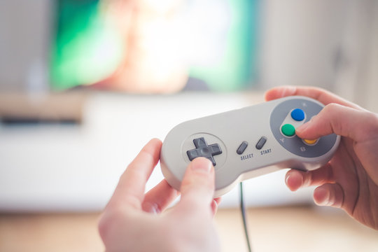 Playing retro video games in living room: Close up of a vintage gaming controller holding in hand